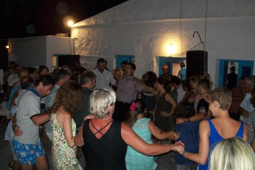 un grupo de personas de pie en una multitud en una fiesta en PATMOS Mathios Studios- apartments, en Patmos