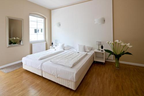 ein weißes Schlafzimmer mit einem großen Bett und einer Vase aus Blumen in der Unterkunft Schnellenburg in Düsseldorf