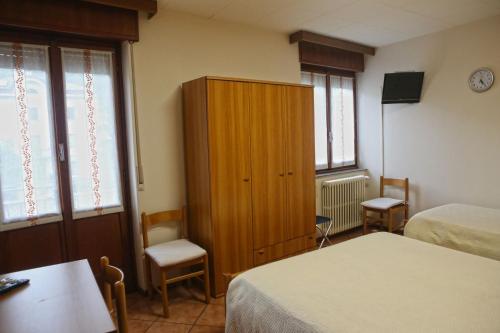 a room with two beds and a cabinet and two chairs at Albergo Gusmeroli in Tirano