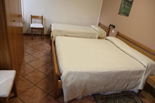 three beds in a room with a chair and a table at Albergo Gusmeroli in Tirano