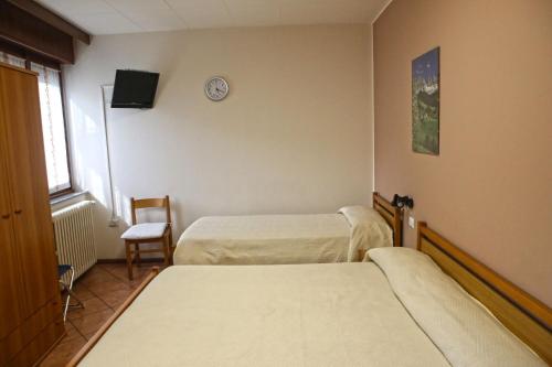 a room with two beds and a clock on the wall at Albergo Gusmeroli in Tirano