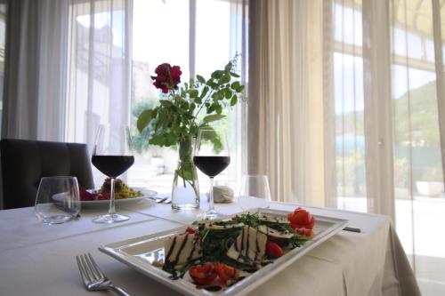 Hotel Terme di Frasassi في جينجا: طاولة مع طبق من الطعام وكؤوس من النبيذ