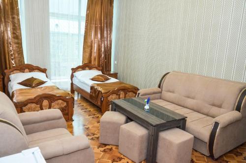 een woonkamer met banken en een tafel en een bed bij Zangezur Hotel in Goris