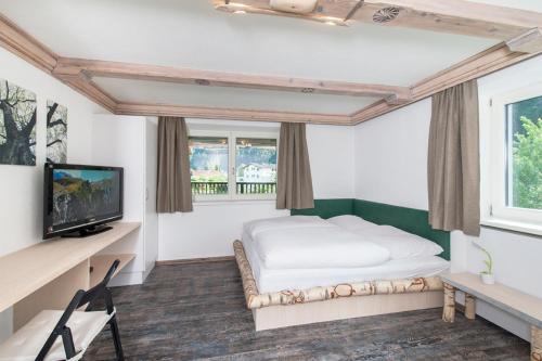 a bedroom with a bed and a tv and windows at Haus Heiss in Prutz