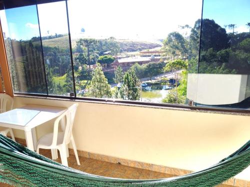 a hammock in a room with a table and a window at Fazenda Morro Pelado in Águas de Lindóia