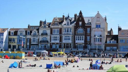 un grupo de personas en una playa frente a los edificios en L'Escale, en Dunkerque