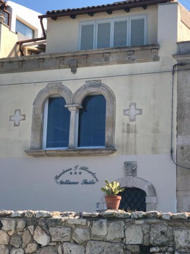 a building with two windows and a potted plant on a wall at Nettuno Suite in Siracusa