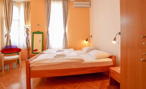 1 dormitorio con 1 cama con sábanas blancas y ventana en Pigeon Square Rooms, en Sarajevo