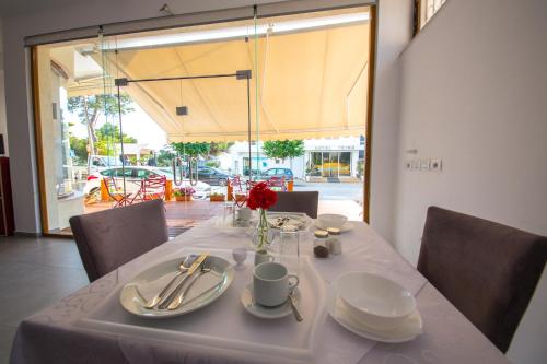 una mesa con mantel blanco y un jarrón con rosas rojas en Hotel Alina, en Sarandë