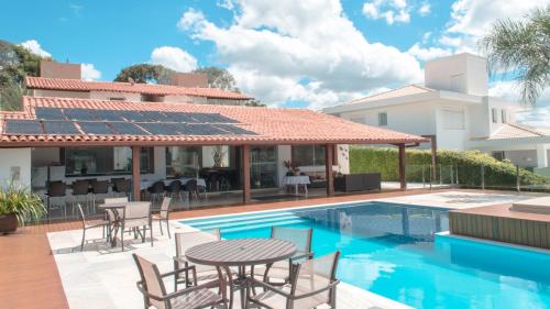 a house with a pool and a table and chairs at Pousada Suítes do Lago in Capitólio