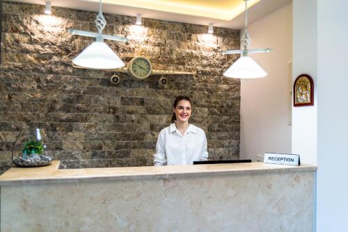 a woman standing behind a counter in a restaurant at B&B Amfora in Petrovac na Moru