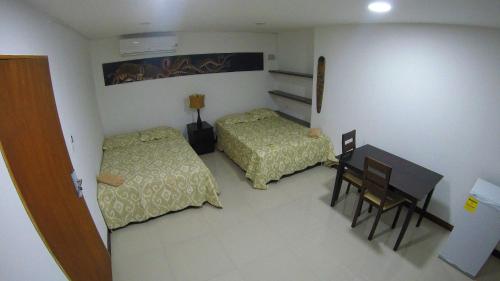 a bedroom with two beds and a desk and a table at Casa Arena San Andres in San Andrés
