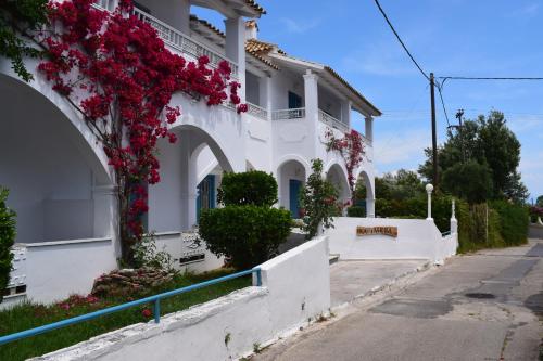 a white house with flowers on the side of it at Kalimera Studios and Apartments in Moraitika