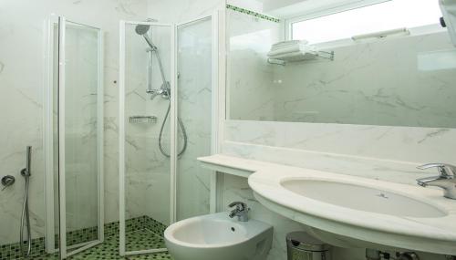 a white bathroom with a sink and a shower at Hotel Wivien in Cesenatico