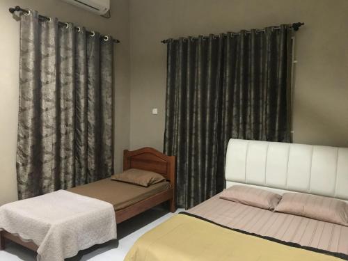 een slaapkamer met 2 bedden en een raam met gordijnen bij Homestay HANI in Arau