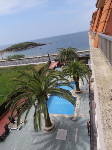 un balcón con vistas a una piscina con palmeras en Hotel Nuevo Lanzada, en A Lanzada