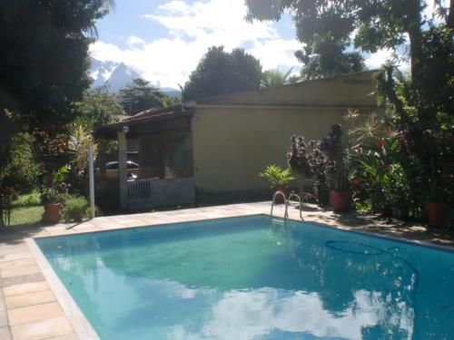 una gran piscina azul frente a una casa en Casa Parada Modelo en Guapimirim