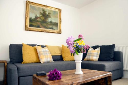 a living room with a blue couch and flowers on a table at Home Crowd Luxury Apartments in Doncaster