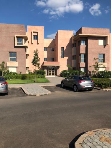 2 voitures garées sur un parking en face d'un immeuble dans l'établissement Prestigia golf pour les familles, à Marrakech