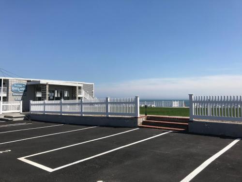 een parkeerplaats met een wit hek naast de oceaan bij The Garlands Motel in Dennis Port