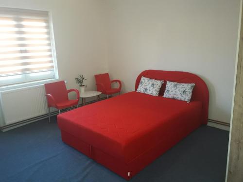 a bedroom with a red bed and two chairs at Guest house Sistem in Brčko
