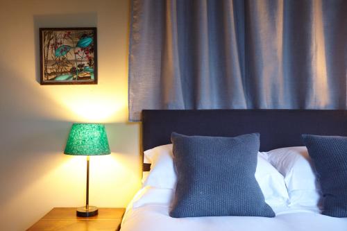 a bedroom with a bed with a lamp and a curtain at The Princess Victoria in London