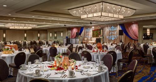 una sala banchetti con tavoli e sedie bianchi e un lampadario a braccio di The Hotel at Auburn University ad Auburn