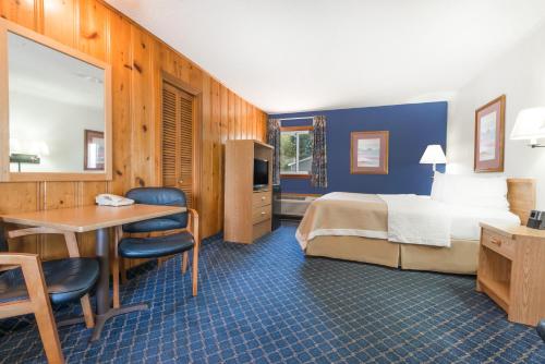 a hotel room with a bed and a desk and a table at Days Inn by Wyndham Worland in Worland