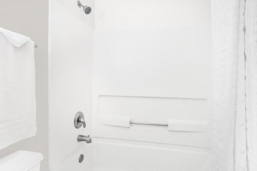Un baño blanco con bañera y lavabo. en Super 8 by Wyndham Bloomfield, en Bloomfield