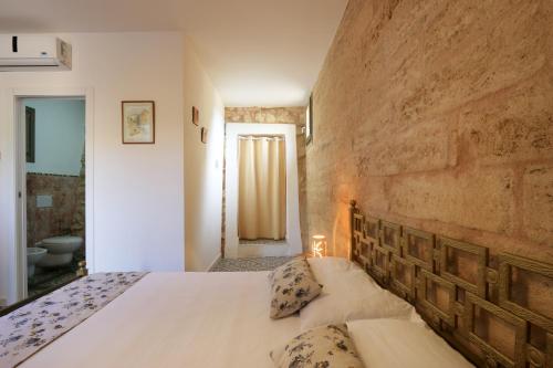 a bedroom with a bed and a brick wall at Allu Ruvezzu in Torre Mozza