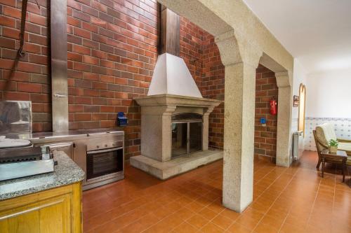 a kitchen with a brick wall with a fireplace at Gião - Porto Green&Pool Villa in Gião