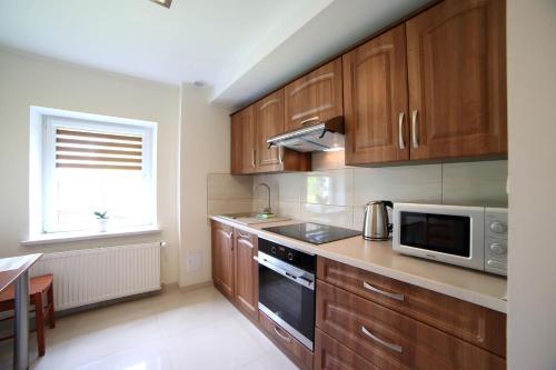 a kitchen with wooden cabinets and a microwave at Apartamenty "Kotlina" in Bystrzyca Kłodzka