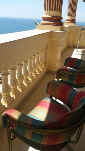 two chairs on a balcony with the ocean in the background at Stanley Bridge Apartment in Alexandria