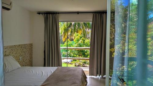 um quarto com uma cama e uma grande janela em Chalé coco b4 em Maceió