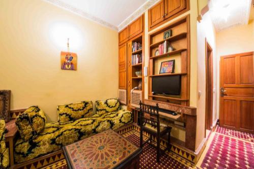 a living room with a couch and a television at Riad Scalia Traditional Guesthouse Fes Morocco in Fès