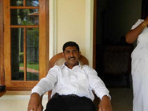 a man in a white shirt sitting in a chair at Ocean View tourist guest house at Negombo beach near the airport in Negombo