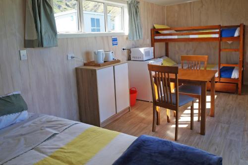 a bedroom with a bed and a desk and a bunk bed at Waimeha Camping Village in Ngawi