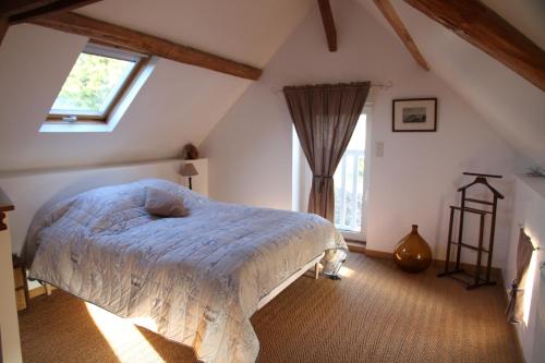 a bedroom with a bed with a blue comforter and a window at Maison St Mayeul in Bouère