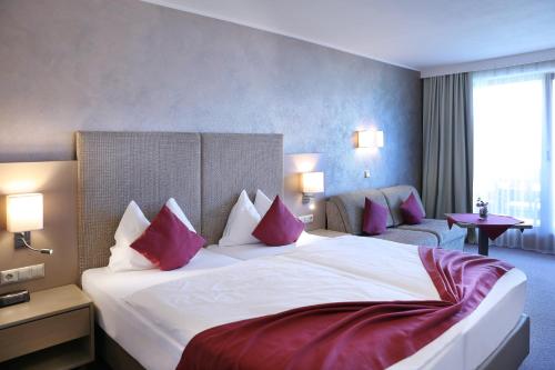 een hotelkamer met een groot bed met rode kussens bij Dei Hotel Schönblick in Velden am Wörthersee