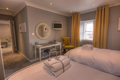 a bedroom with two beds and a desk and a mirror at Thistle Apartment in Golspie