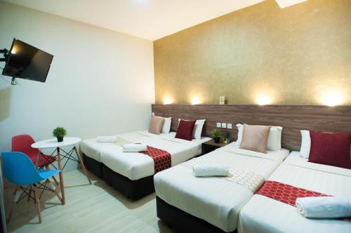 a hotel room with three beds and a table at DJ Citi Point Hotel in Kuala Terengganu