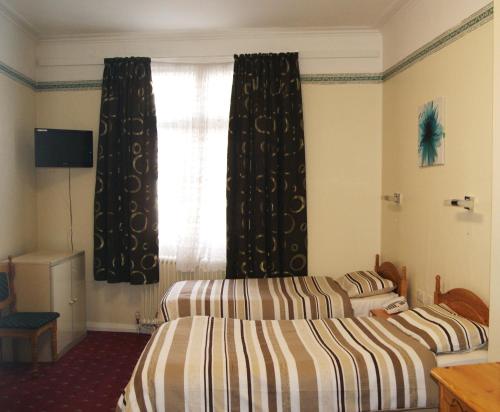 a hotel room with two beds and a window at Stanley House Hotel in London