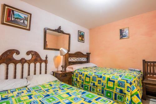 a bedroom with two beds and a mirror at Casa De Leon in Antigua Guatemala