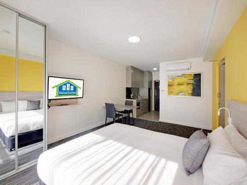 a hotel room with a bed and a desk at Value Suites Penrith in Penrith