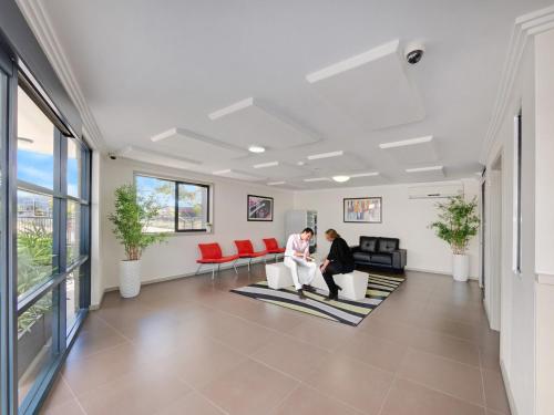 two people sitting on chairs in a living room at Value Suites Penrith in Penrith