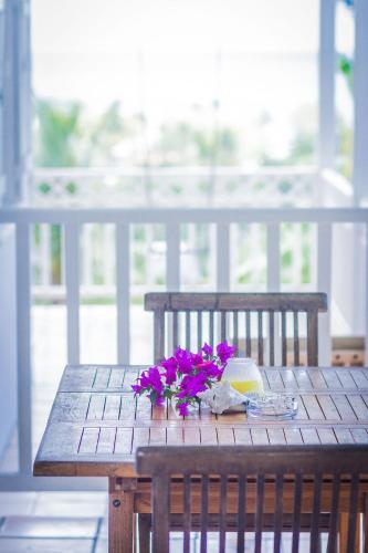 a wooden table with purple flowers on top of it at Carre Royal in Deshaies