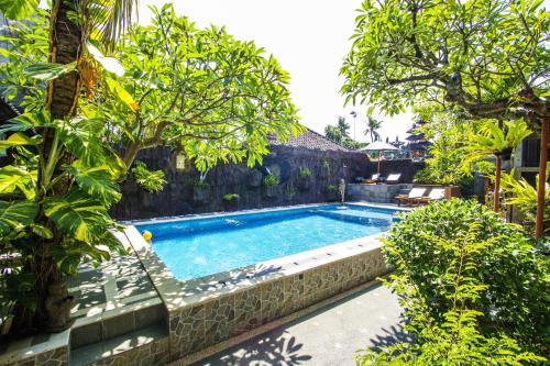 una piscina en un jardín con árboles en Hotel Shri Ganesh, en Lovina