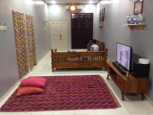 a room with a crib and a television and a rug at TeratakMuslim H'H in Melaka