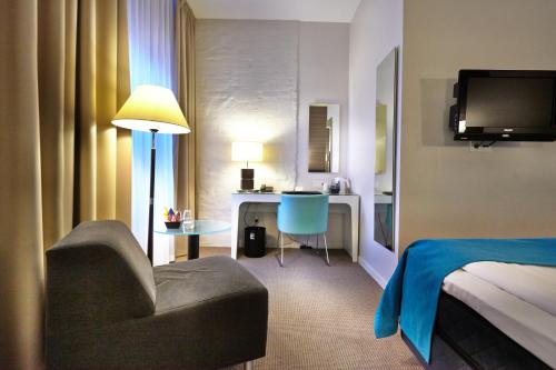 a hotel room with a bed and a chair and a desk at Elite Stadshotellet Växjö in Växjö