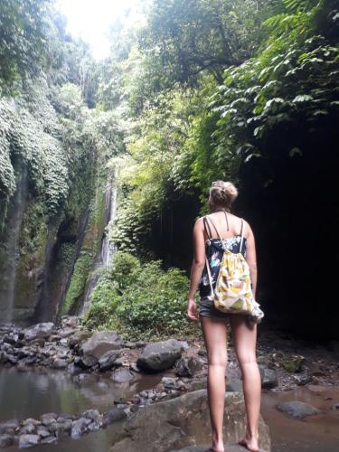 a woman standing in a river looking at a waterfall at Sugi Gede Homestay in Singaraja